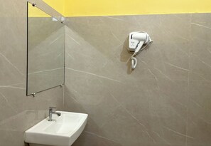 Ein Badezimmer mit Spiegel, Waschbecken und an der Wand montiertem Föhn.