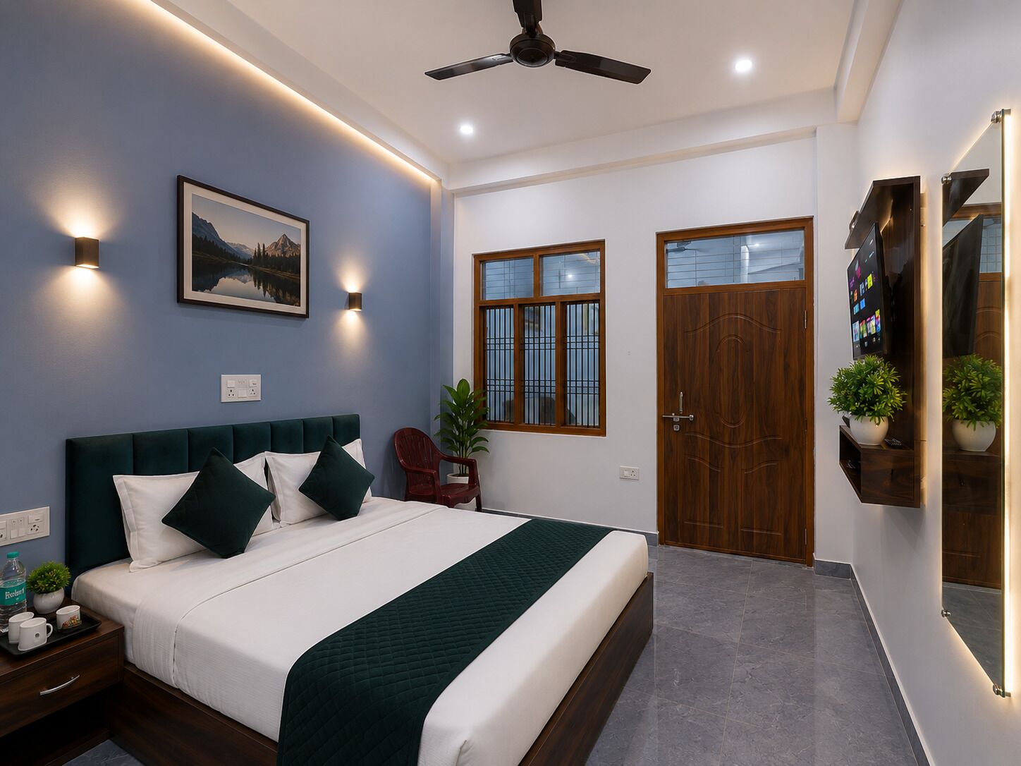 A bedroom with a bed, bedside table, wall-mounted TV, ceiling fan, and a window with bars.