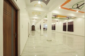 A hotel corridor with a wooden door, white walls, marble flooring, and ceiling artwork. - Hotel The Viraj Palace (Ayodhya)