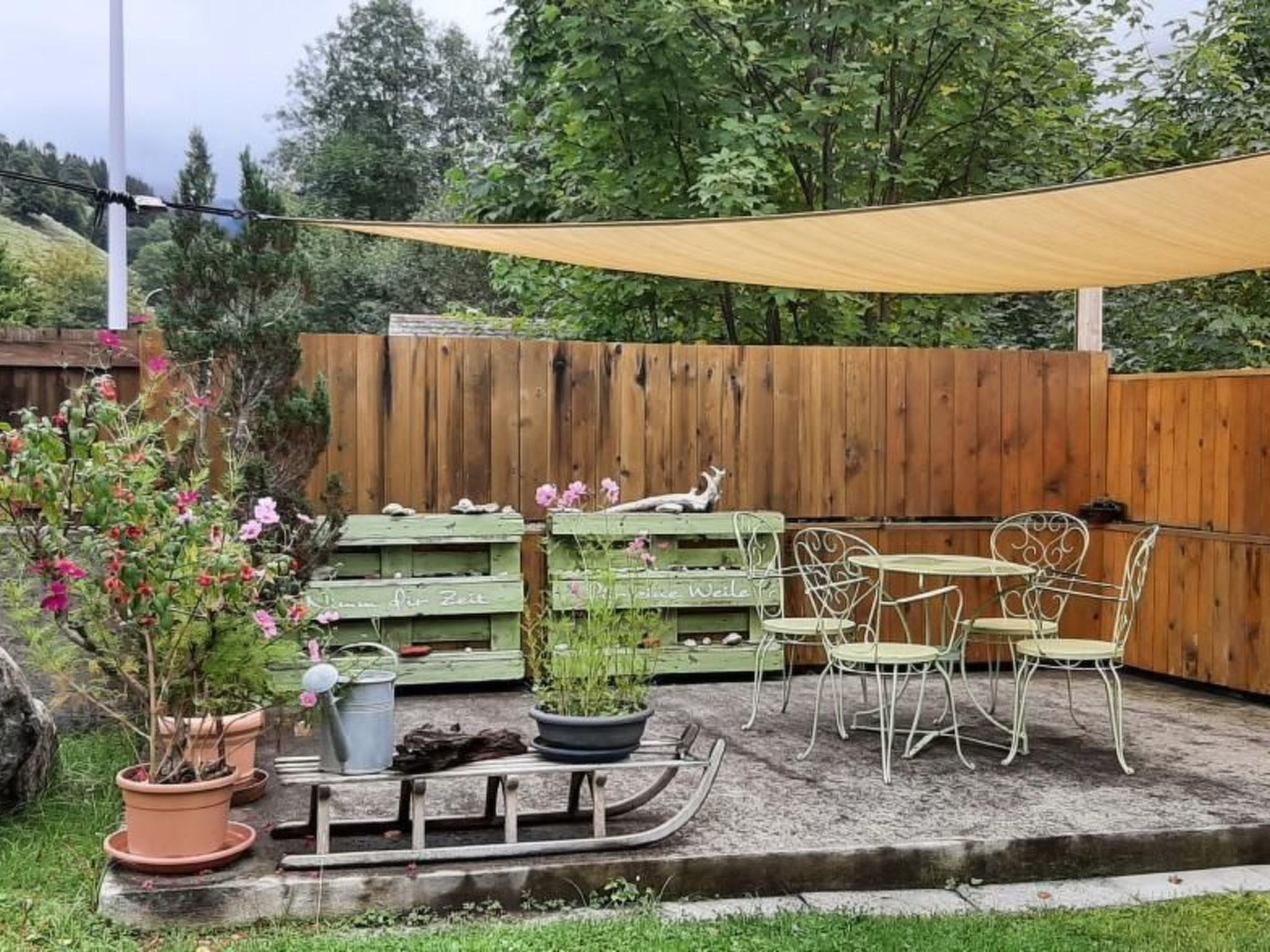 Un patio con cerca de madera, mobiliario exterior y plantas en macetas.