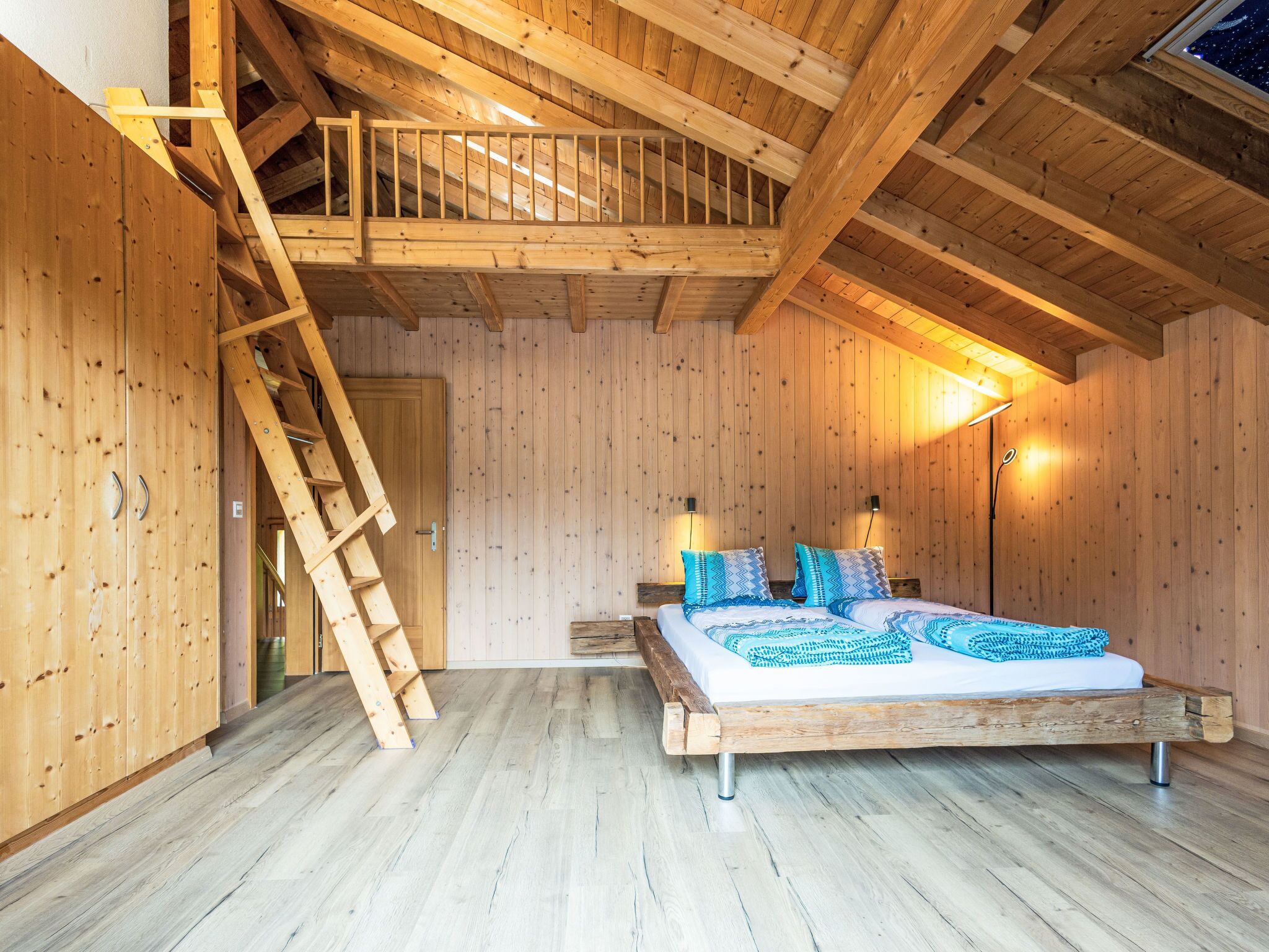 A wooden room with a loft bed, a ladder, and a nightstand.