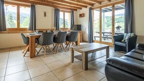 A dining area with a wooden table and chairs, a television, and a sofa. - Stöckli auf dem Birkenhof mit Zusatzzimmer by Interhome (Sörenberg)