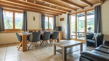 A dining area with a wooden table and chairs, a television, and a sofa.