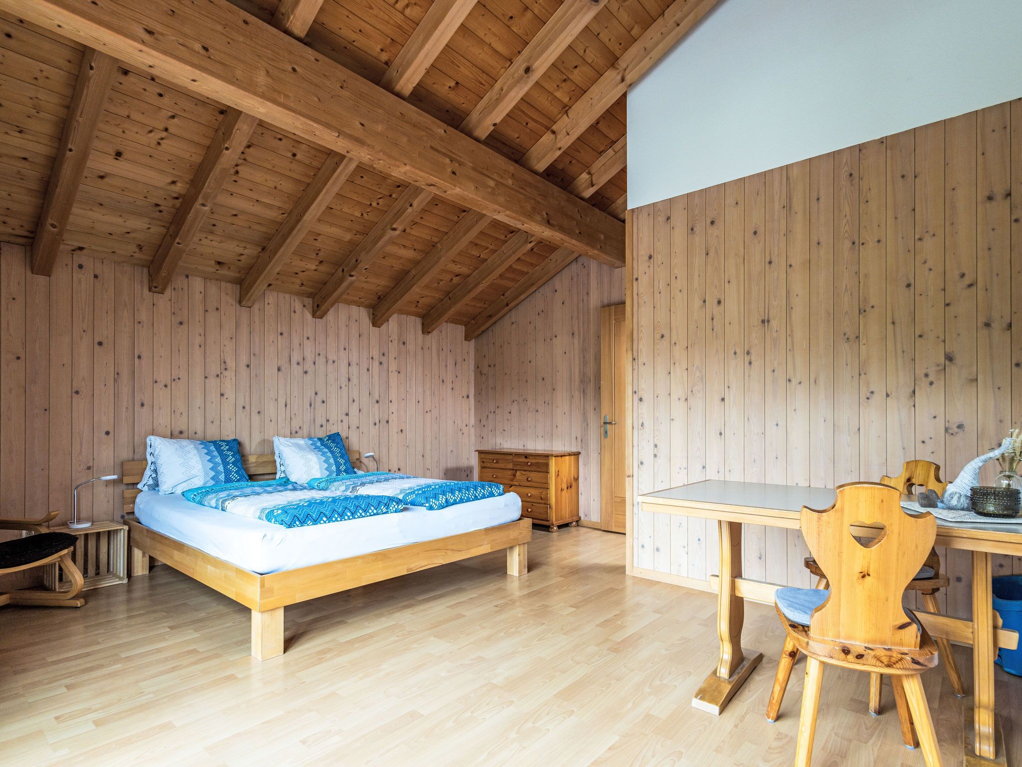 Una habitación con paneles de madera, una cama, una mesa y una silla.