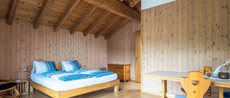 Una habitación con paneles de madera, una cama, una mesa y una silla.