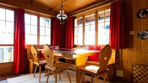 Ein Essbereich aus Holz mit einem großen Tisch, Stühlen und roten Vorhängen.