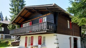 Ein zweistöckiges Haus mit Balkon, einer kleinen Sitzecke und einer Steinmauer.