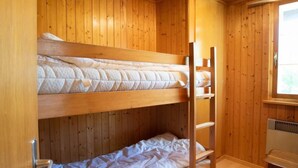 Ein Schlafraum mit Etagenbetten, Holzwänden und einem Fenster.