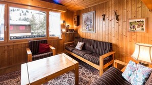 Ein gemütliches Holzhaus-Interieur mit einer Couch, einem Sessel und einem Tisch.