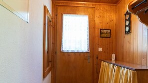 Una puerta de madera con un ventanal, un reloj de pared y una cortina amarilla.