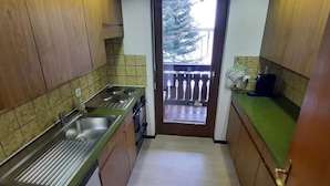 Una cucina compatta con lavandino, piano cottura e un piccolo balcone con ringhiera.