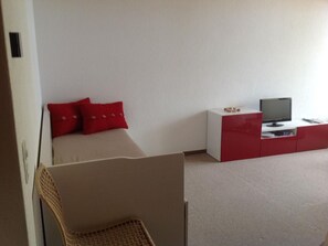 Ein Schlafzimmer mit einem Bett, einem Fernseher und einer roten und weißen Kommode.