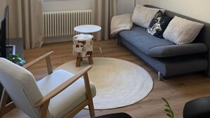 Un soggiorno moderno con un divano, un tavolino rotondo, una poltrona e una lampada da terra.