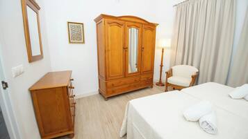 Una habitación de hotel con una cama, un armario de madera, una silla y una lámpara.