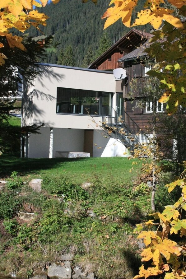 Una casa moderna de dos plantas con techo plano, ventanas amplias y una antena parabólica visible.