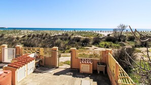 A beach view with a gated entrance, outdoor seating, and a clear sky. - La Playa Wohnung - direkt am Strand by Interhome (La Caletta)