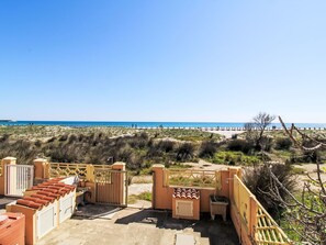 Blick auf einen Strand mit geschlossenem Eingang, Außenbereich mit Sitzgelegenheiten und blauem Himmel.