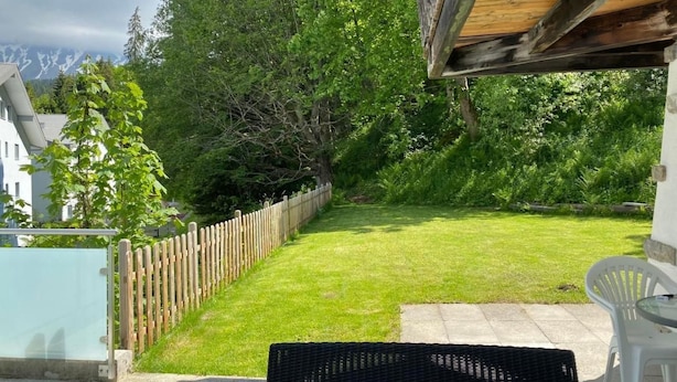 A patio area with a wooden fence, a grassy lawn, and a view of a mountain range.