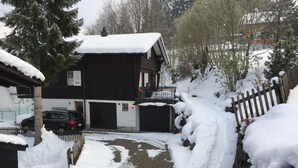 A two-story building with a snow-covered roof and a paved driveway leading to a garage.