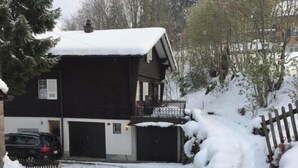 A two-story house with a snow-covered roof and a balcony.