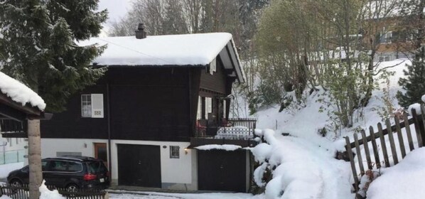 A two-story house with a snow-covered roof and a balcony.