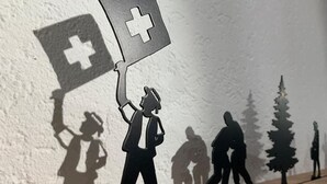 Eine Silhouette einer Person, die ein medizinisches Kreuz hält, mit weiteren Silhouetten im Hintergrund.