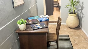 A desk with books, a potted plant, and a chair in a room with a tiled floor and a framed picture on the wall. - 'Casa Donna Giovanna by Interhome (Chia)