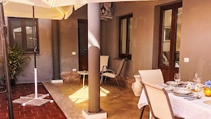 An outdoor dining area with a table set for two, a potted plant, and a brick floor. - 'Casa Donna Giovanna by Interhome (Chia)