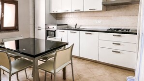 Una cucina moderna con mobili bianchi, un piano di lavoro nero e un fornello a gas.