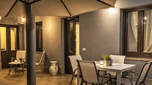 An outdoor dining area with a table and chairs, a potted plant, and a vase. - 'Casa Donna Giovanna by Interhome (Chia)