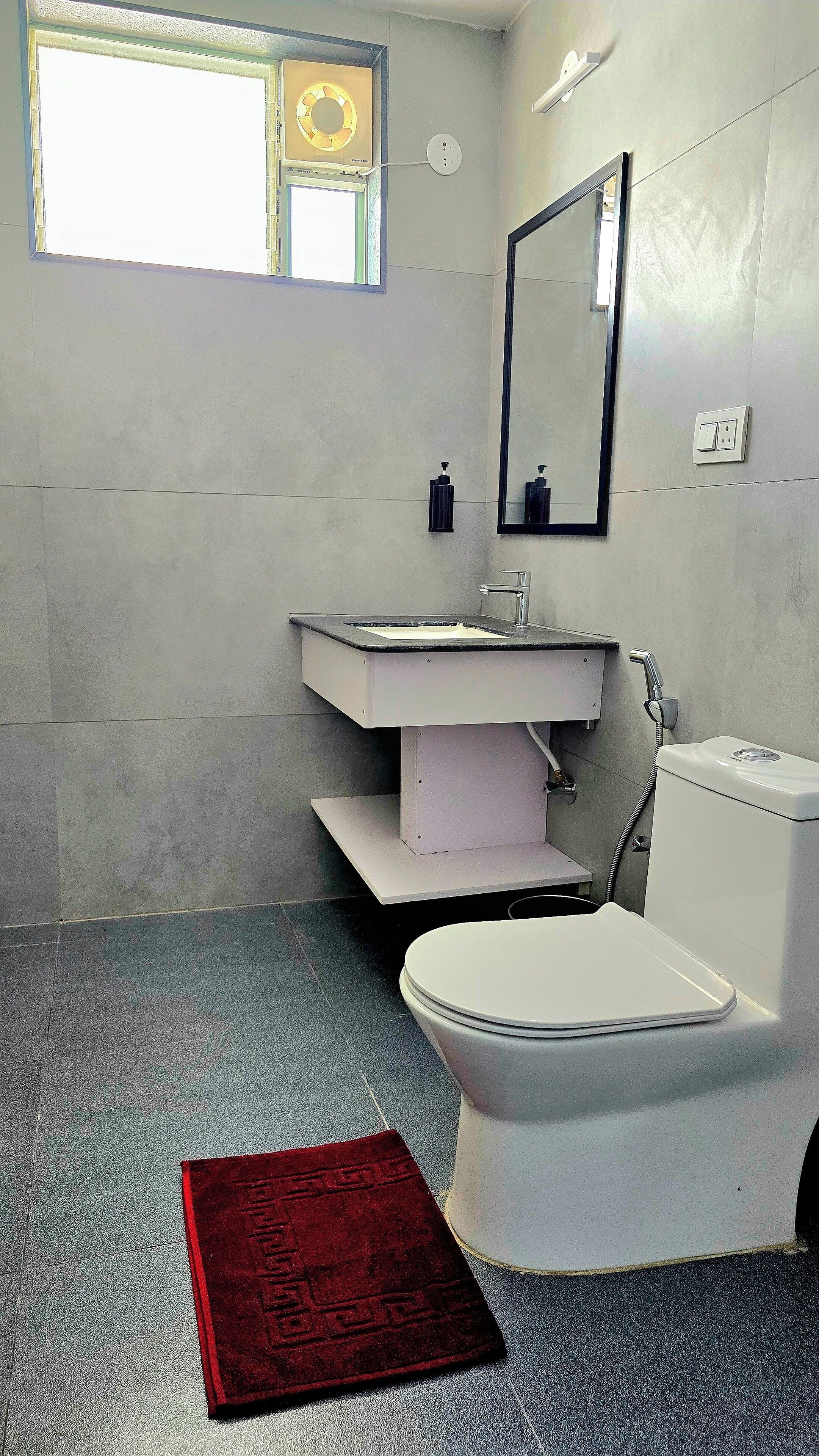 Un baño con inodoro, lavamanos y espejo.