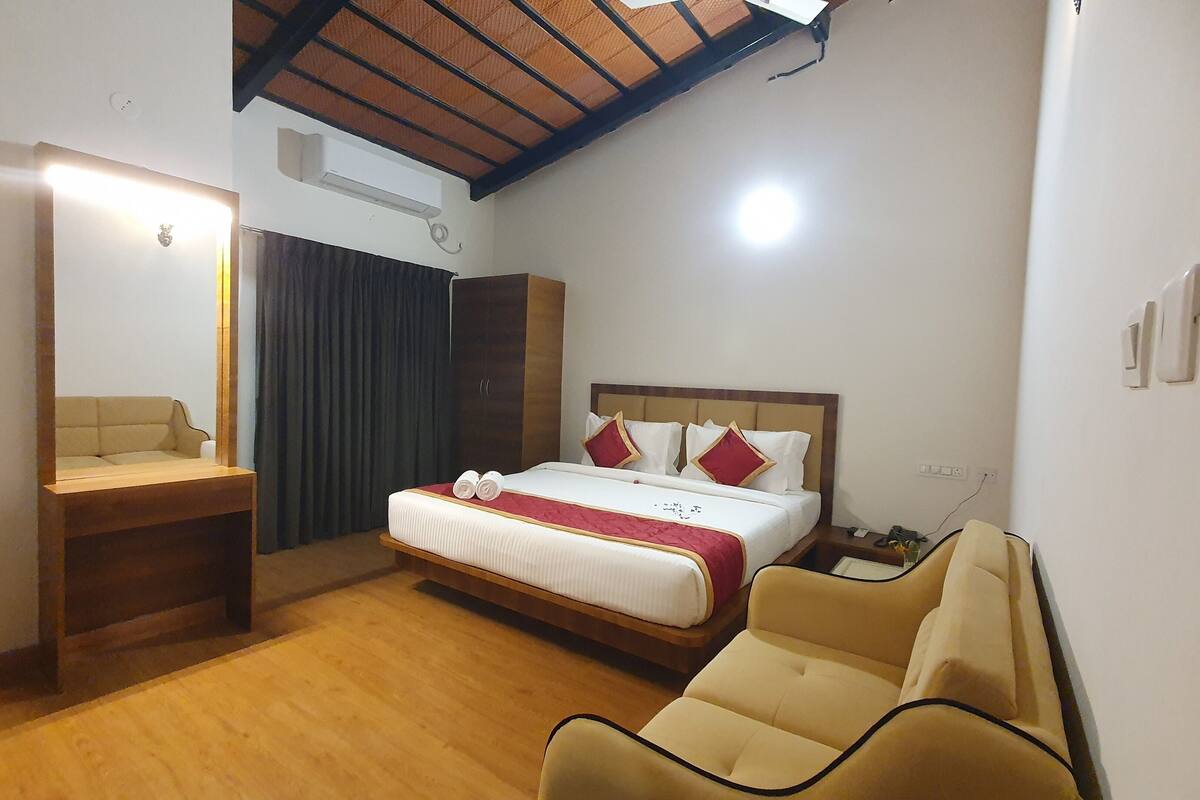A hotel room with a bed, a bedside table, a chair, a wardrobe, and a ceiling fan.