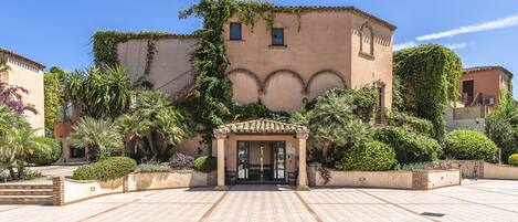 A courtyard with a building featuring arches and a tiled entrance.