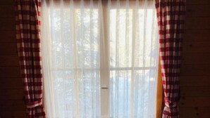 A room with a bed, a window with sheer curtains, and a radiator. - Chalet Bacchus (EG) by Interhome (Sörenberg)