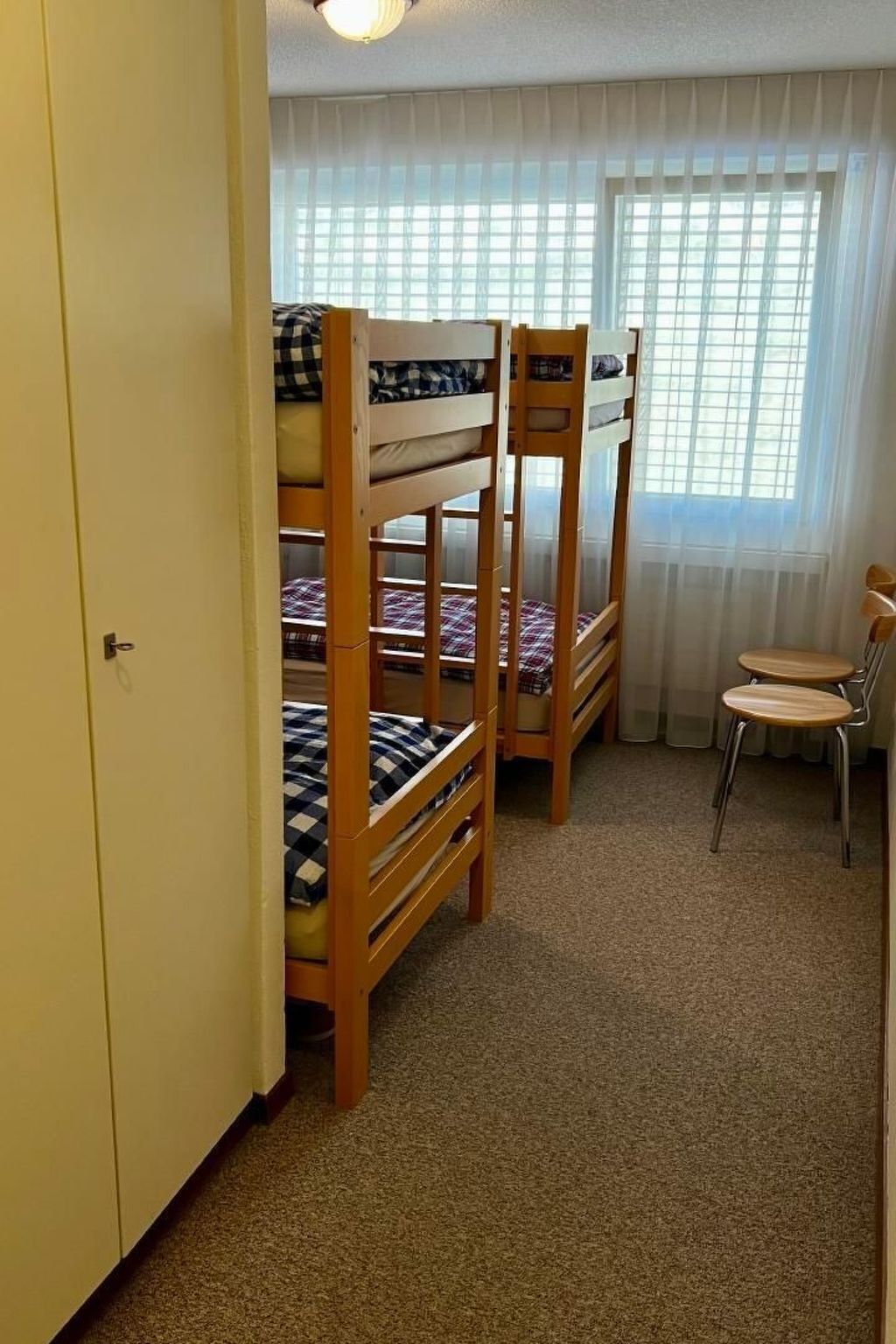 Een slaapzaal met stapelbedden, een bureau en een stoel.