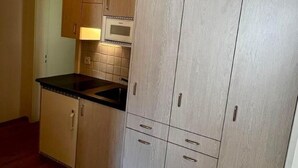 A kitchen with wooden cabinets, a black countertop, and a microwave.