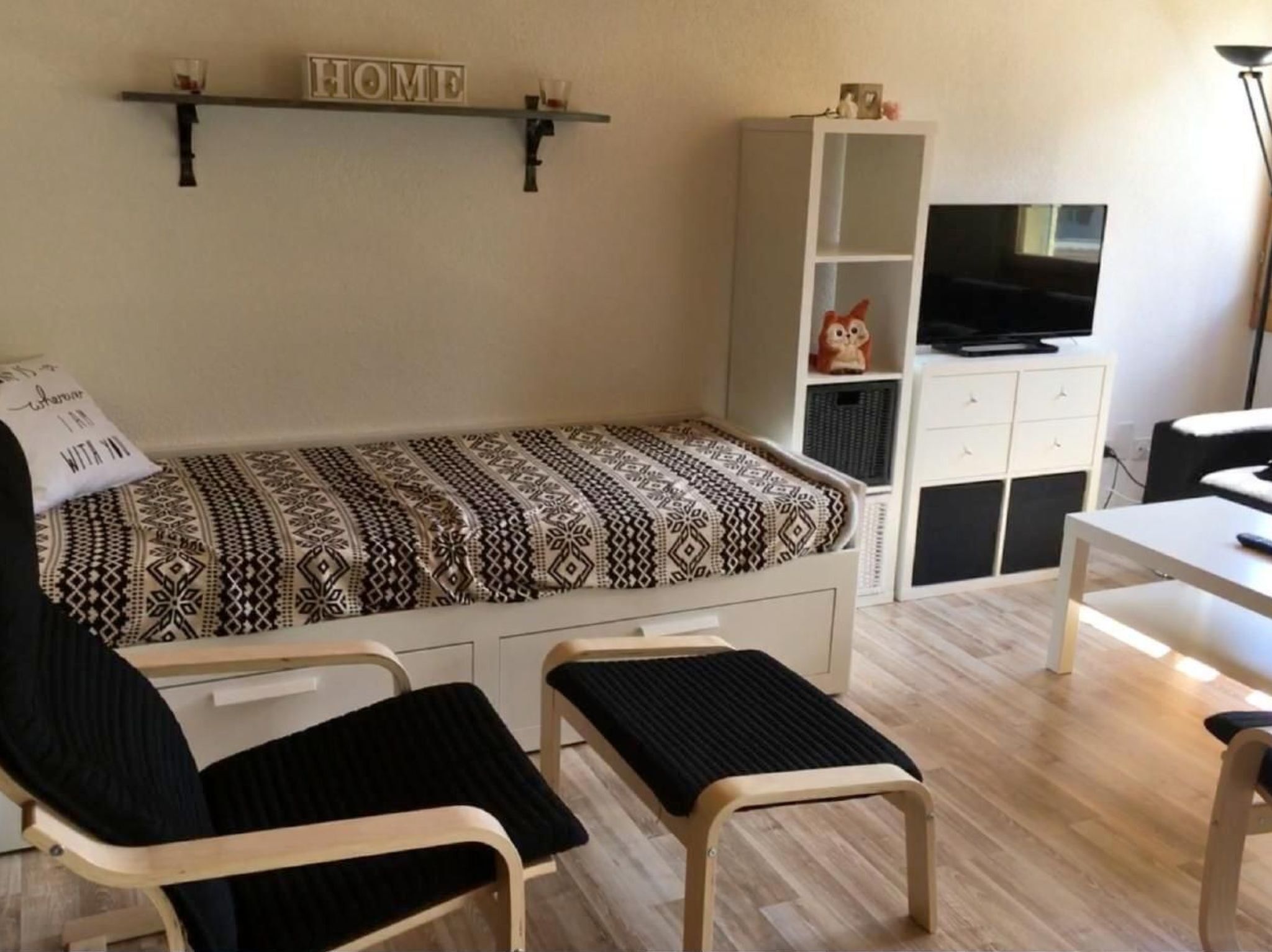 Ein kleiner, gemütlicher Raum mit einem Bett, zwei Sesseln, einem Fernseher und einem Schrank.