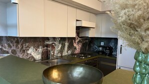 Eine moderne Küche mit weißen Schränken, einer Granit-Spritzschutzleiste und einer Edelstahl-Spüle.