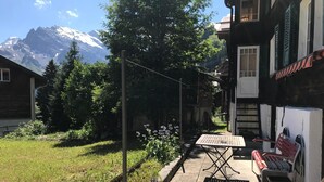 A courtyard with a table and chairs, a small garden, and a mountain view. - Chalet Alpenblick 4-Bett Wohnung by Interhome (Lauterbrunnen)