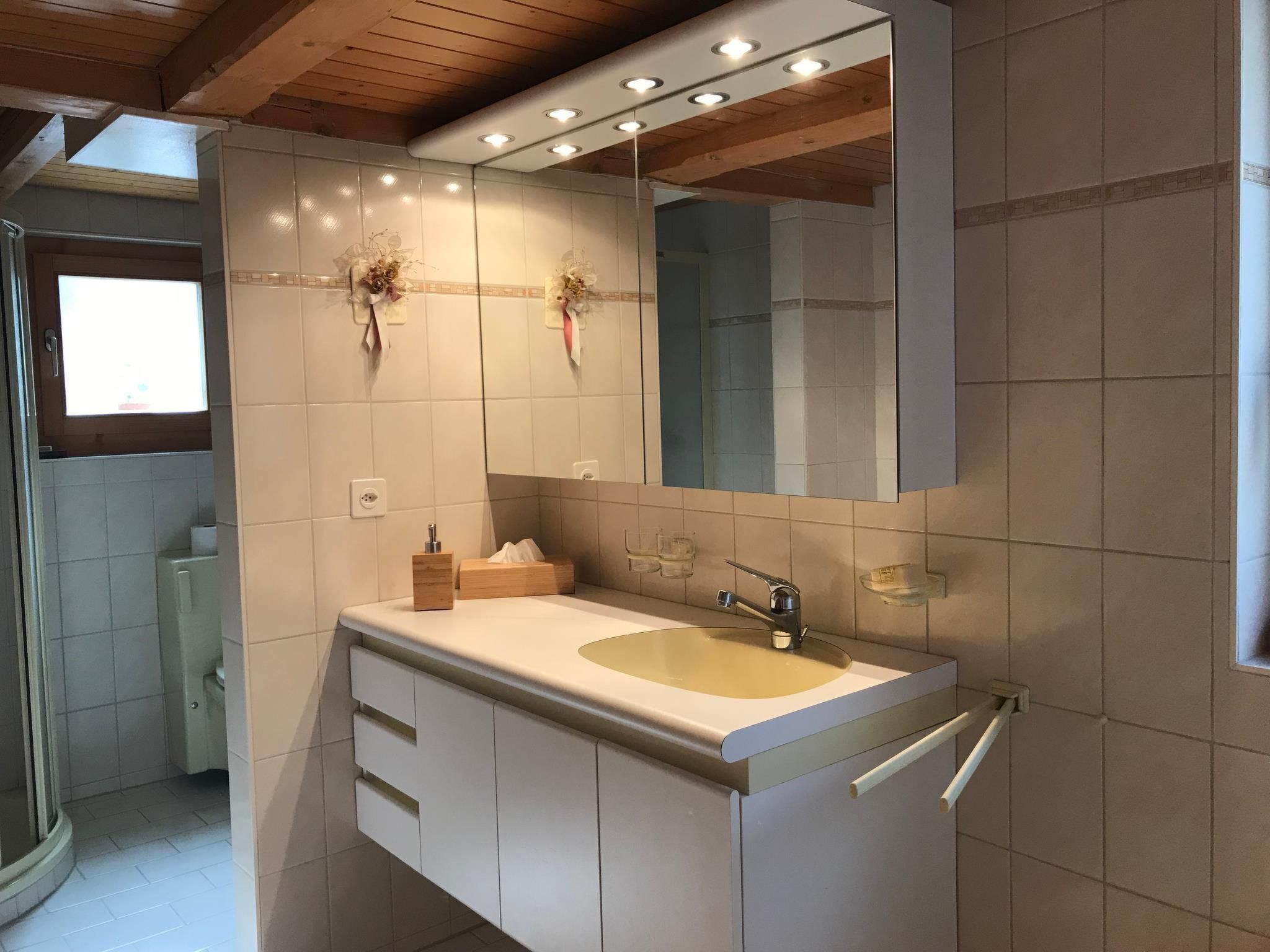 Ein Badezimmer mit großem Spiegel, Waschbecken und Duschbereich.