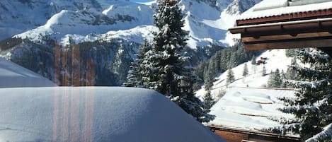 A snow-covered mountain landscape with a building featuring a sloped roof and wooden exterior.
