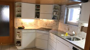 A compact kitchen with white cabinets, a granite countertop, a built-in dishwasher, and a window above the sink. - Chalet Alpenblick 4-Bett Wohnung by Interhome (Lauterbrunnen)