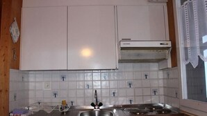Una cocina con armarios blancos, un lavamanos de acero inoxidable y una estufa.