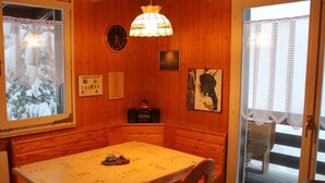Un comedor acogedor con una mesa de madera, sillas, un reloj y cuadros en la pared.