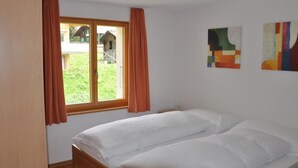 Un dormitorio con una cama individual, una ventana con cortinas y dos cuadros abstractos en la pared.