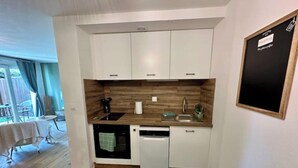 Eine kleine Küche mit weißen Schränken, einer Holz-Spritzschutzwand, einer Spüle und einem Geschirrspüler.