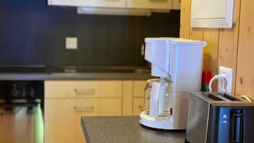 Een koelkast, een microgolfoven, een oven, kookgerei, borden en bestek