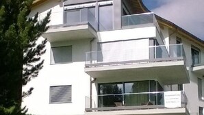 Ein mehrstöckiges Wohngebäude mit Balkonen, großen Fenstern und einem Steinfundament.