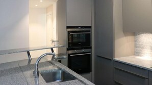 Eine moderne Küche mit Granit Arbeitsplatten, Edelstahlgeräten und einem minimalistischen Design.