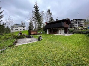 A modern house with a large lawn, a wooden deck, and a stone fireplace. - Chalet Bambi by Interhome (Sörenberg)